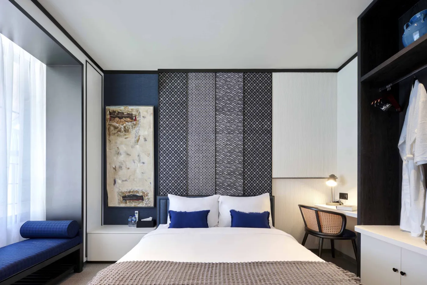 Modern open-plan room with blue mosaic tiled kitchen island, bar stools, blue sofa, bed, and large windows overlooking tropical garden. - Bali Villas