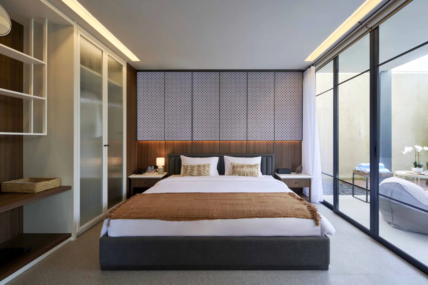 Modern open-plan room with blue mosaic tiled kitchen island, bar stools, blue sofa, bed, and large windows overlooking tropical garden. - Bali Villas