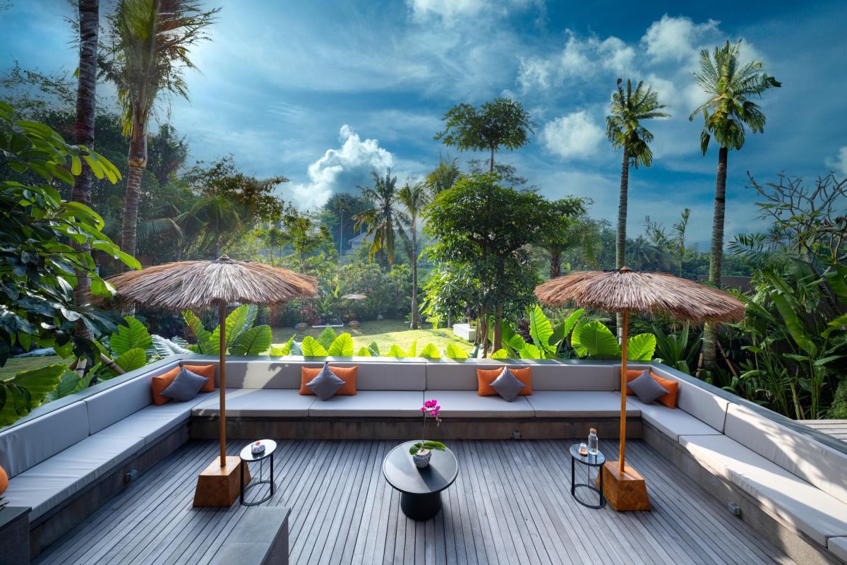 Modern luxury bathroom with freestanding white bathtub, gray stone walls, glass shower, and minimalist vanity. - Bali Villas