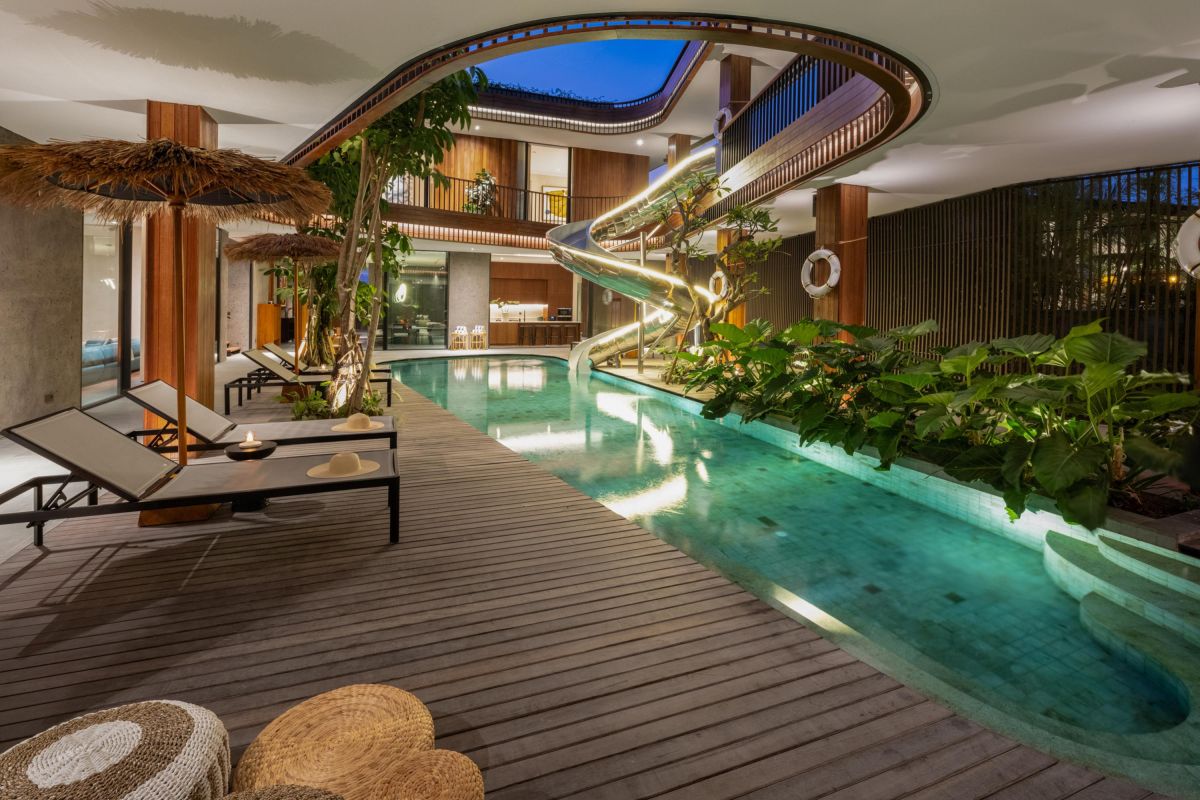 Modern luxury bathroom with freestanding white bathtub, gray stone walls, glass shower, and minimalist vanity. - Bali Villas