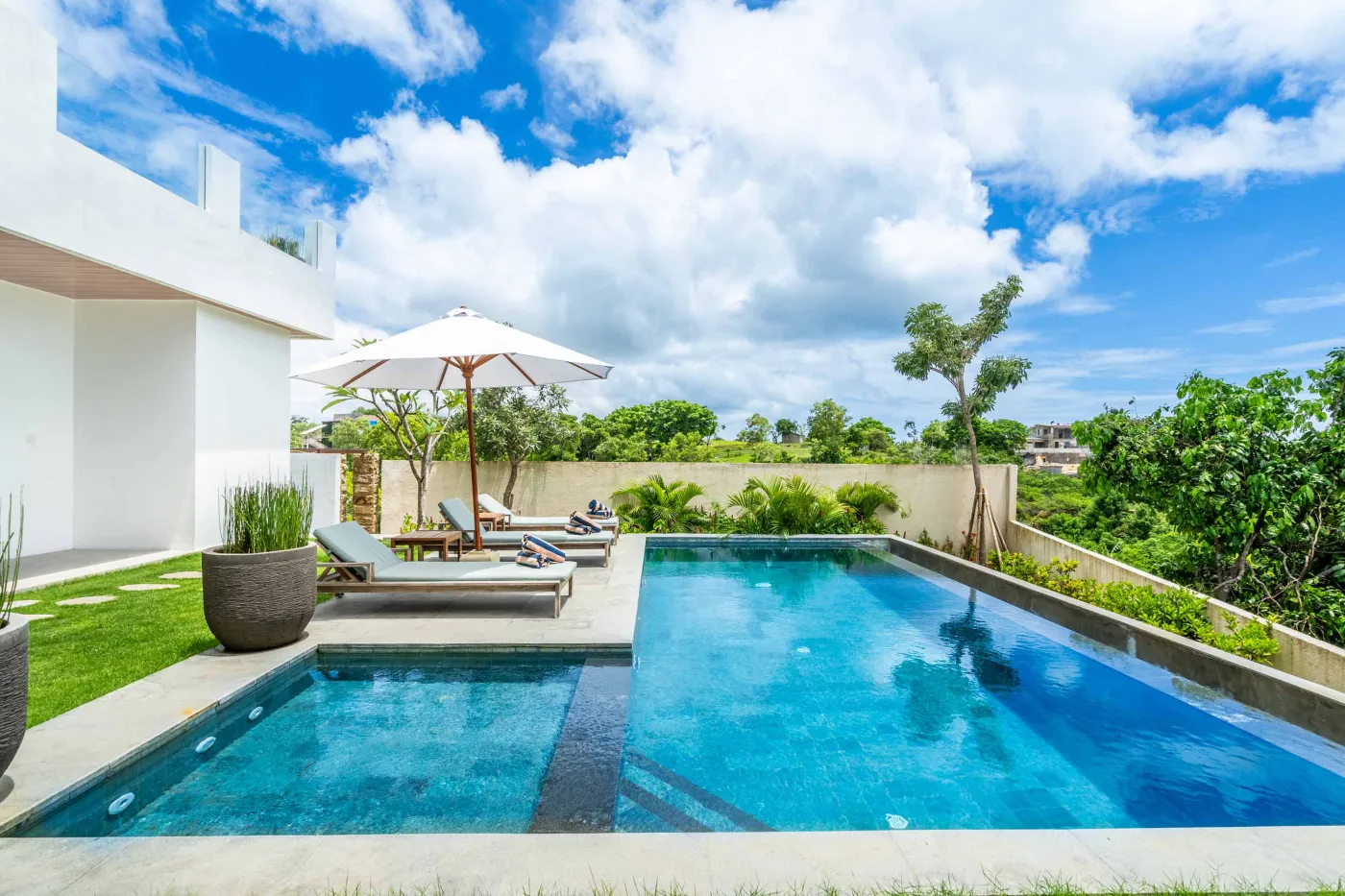 Blue and white striped towels rolled on a teal poolside lounger at a tropical resort villa. - Bali Villas