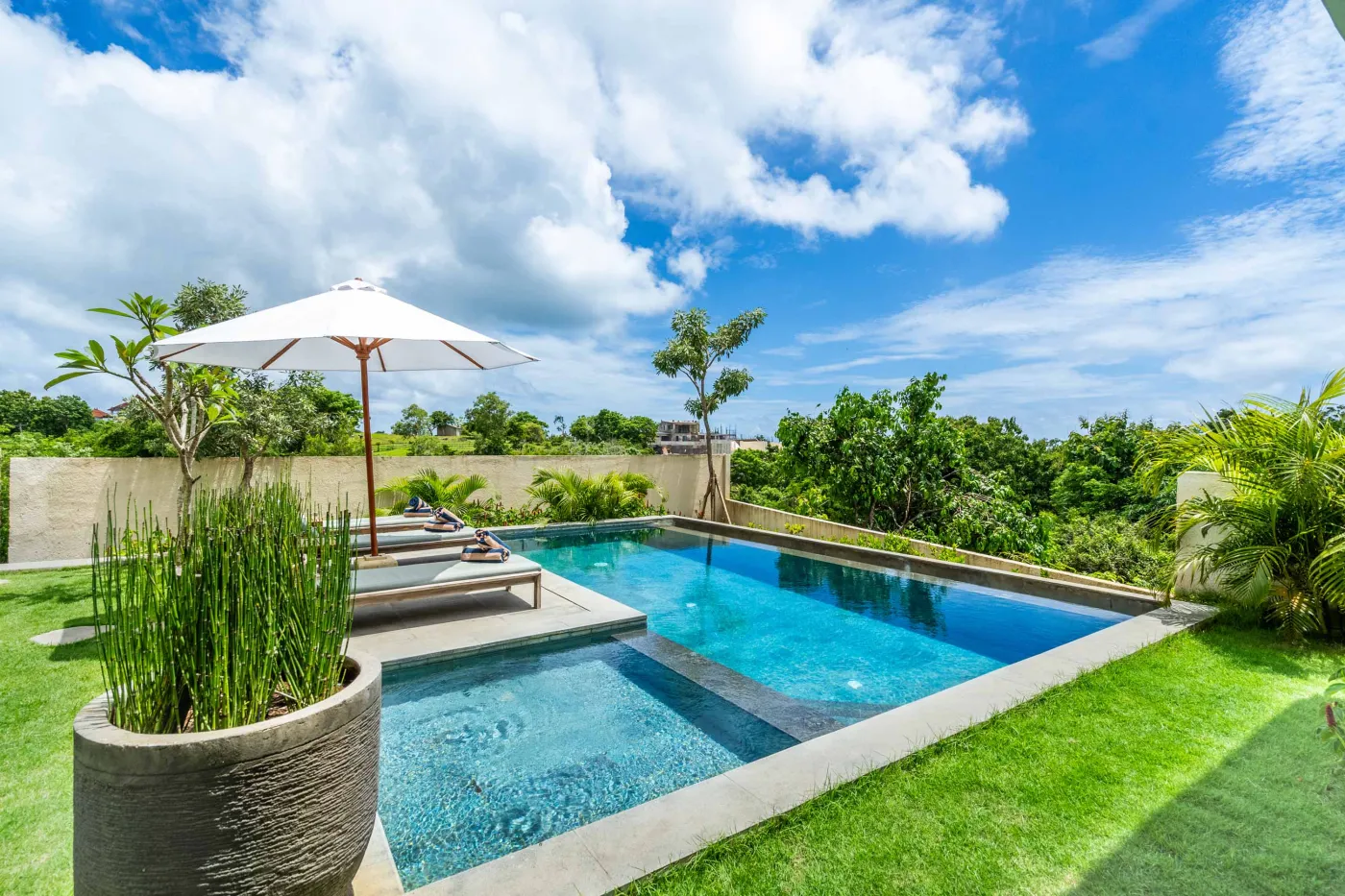 Blue and white striped towels rolled on a teal poolside lounger at a tropical resort villa. - Bali Villas
