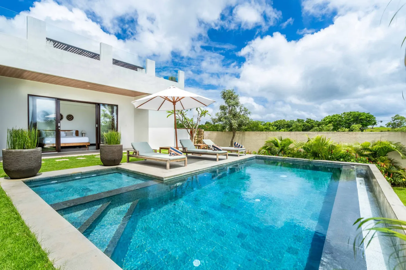 Blue and white striped towels rolled on a teal poolside lounger at a tropical resort villa. - Bali Villas
