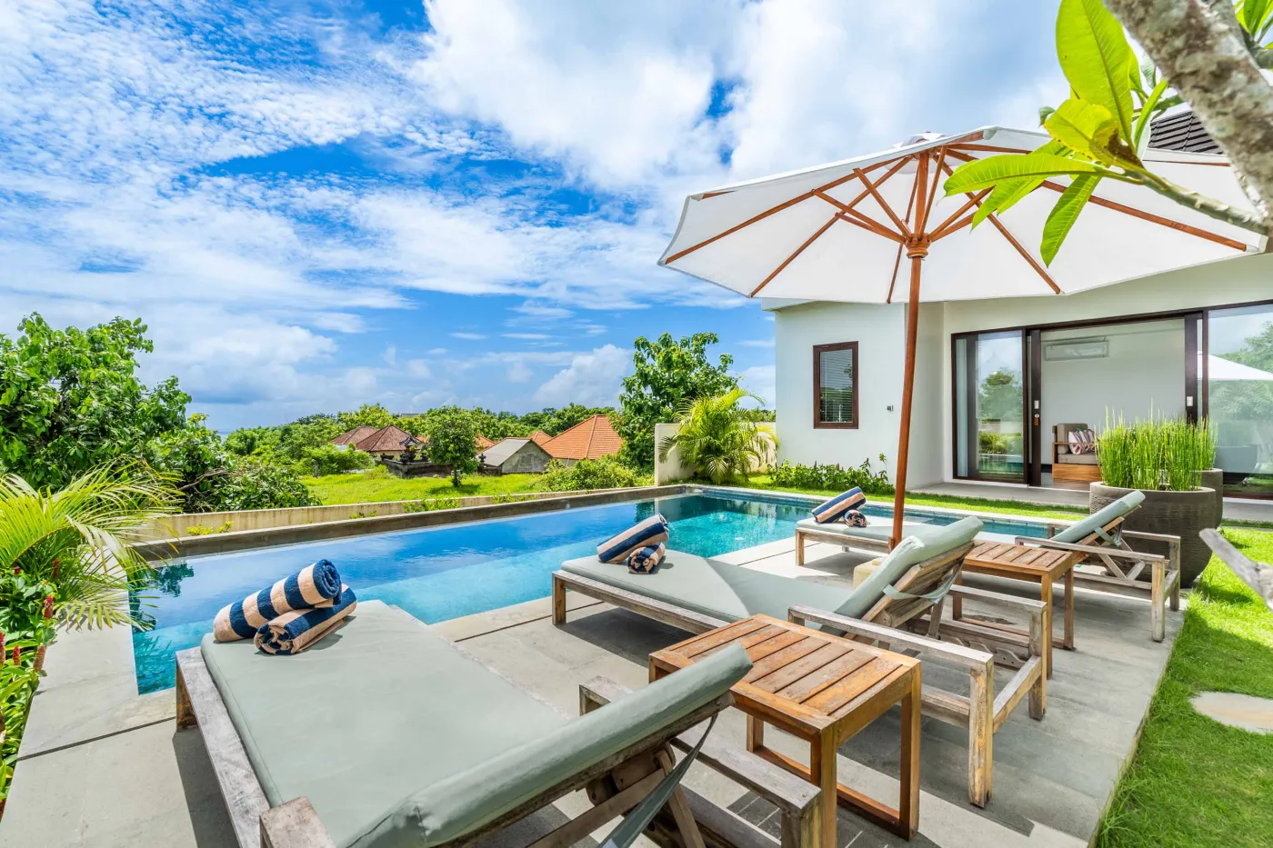 Luxury tropical villa infinity pool with loungers, towels, and scenic rice field views in Bali. - Bali Villas