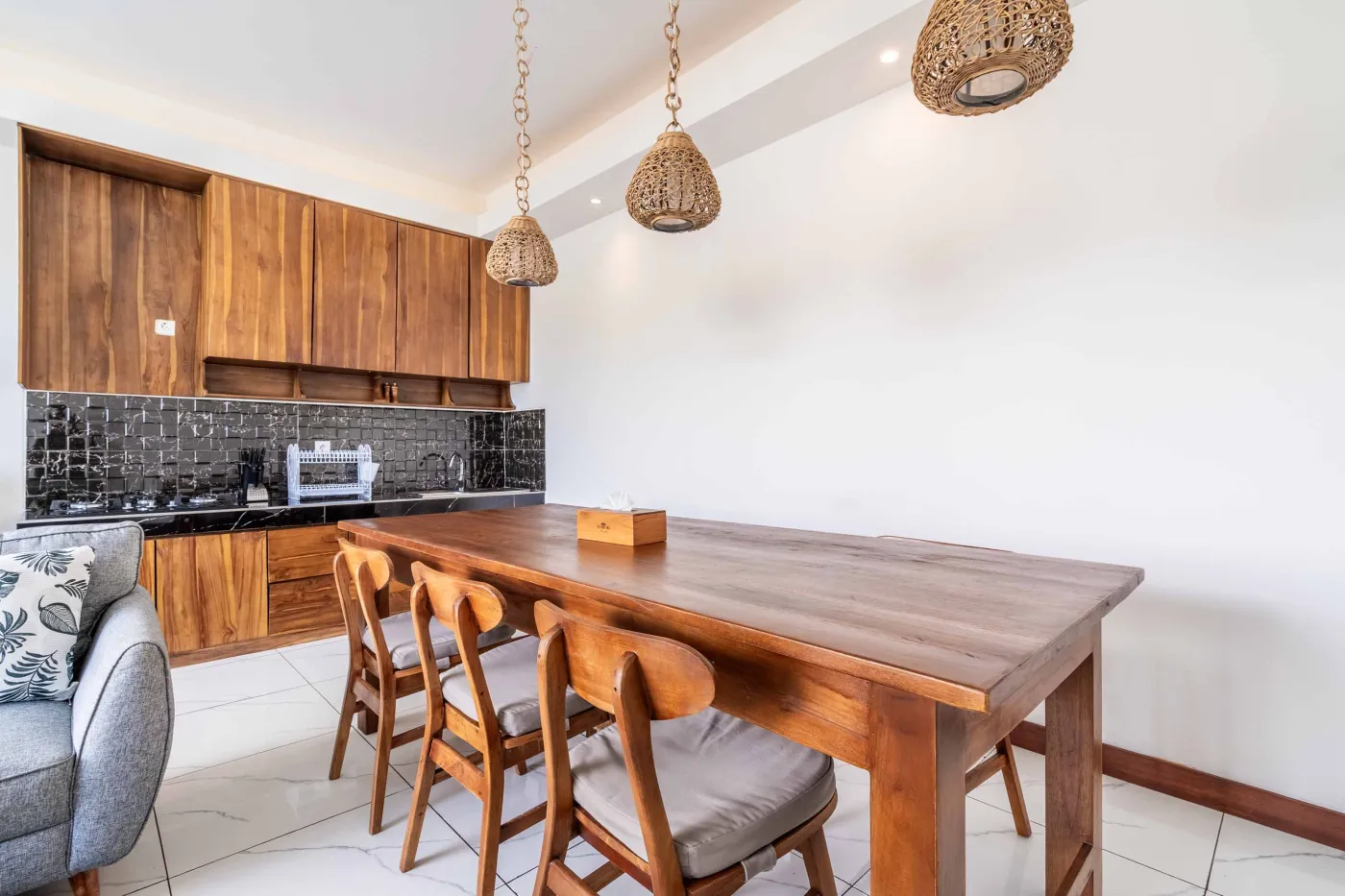 Modern tropical bathroom featuring brick-tiled shower, wooden vanity sink, toilet, and woven accents. - Bali Villas