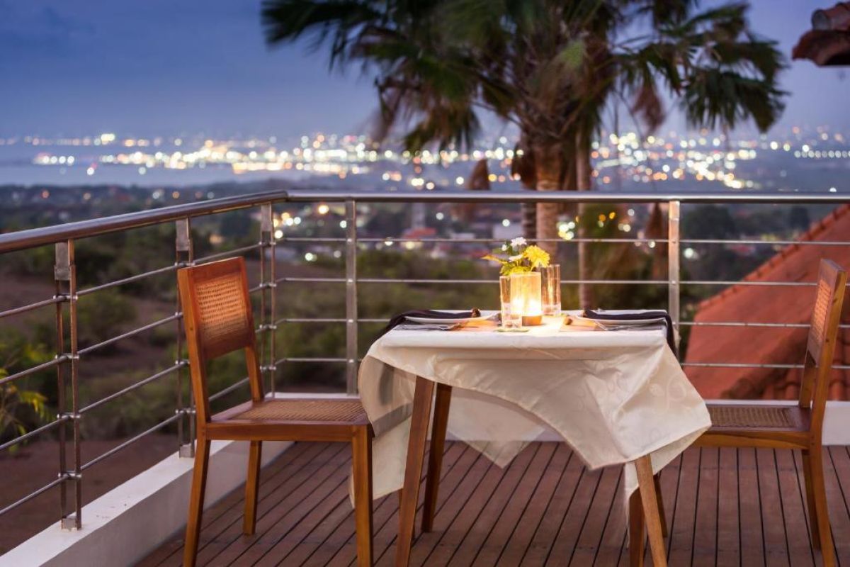 Twilight infinity pool with glowing blue water, lounge chairs on wooden deck, and modern resort architecture at dusk. - Bali Villas