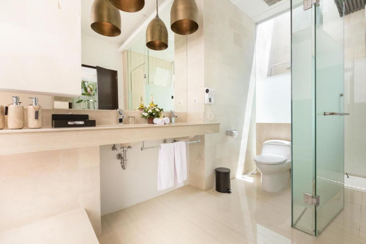 Twilight infinity pool with glowing blue water, lounge chairs on wooden deck, and modern resort architecture at dusk. - Bali Villas