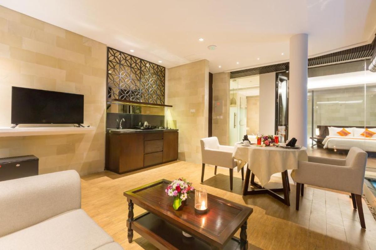 Twilight infinity pool with glowing blue water, lounge chairs on wooden deck, and modern resort architecture at dusk. - Bali Villas