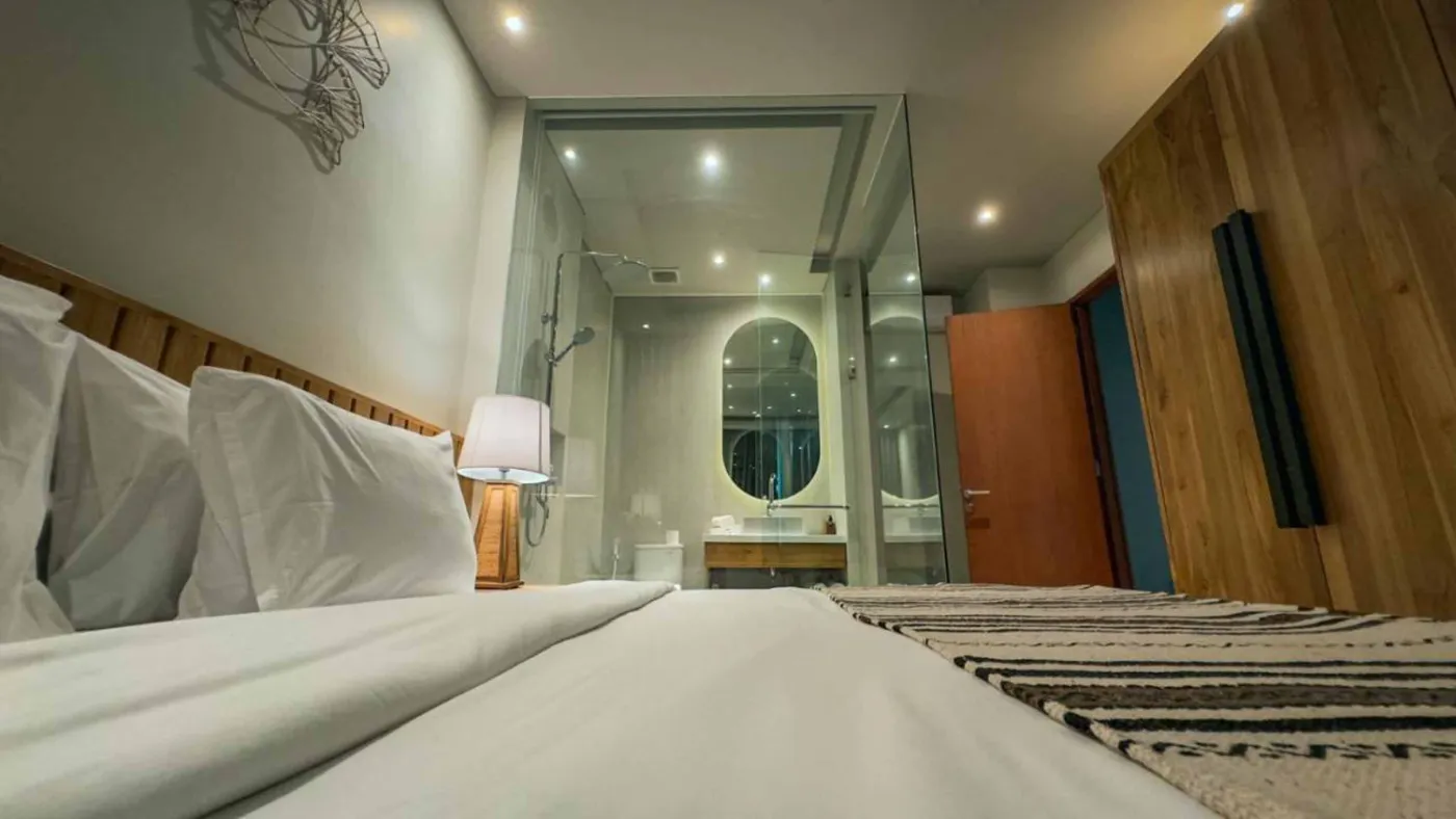 Modern Balinese villa interior: open kitchen with wooden cabinets, granite island, tiled backsplash, and dining table with pink orchids, overlooking a green balcony. - Bali Villas