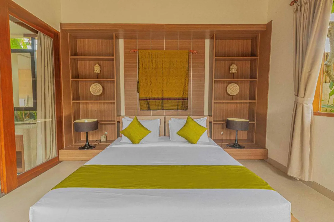 Modern Balinese villa interior: open kitchen with wooden cabinets, granite island, tiled backsplash, and dining table with pink orchids, overlooking a green balcony. - Bali Villas