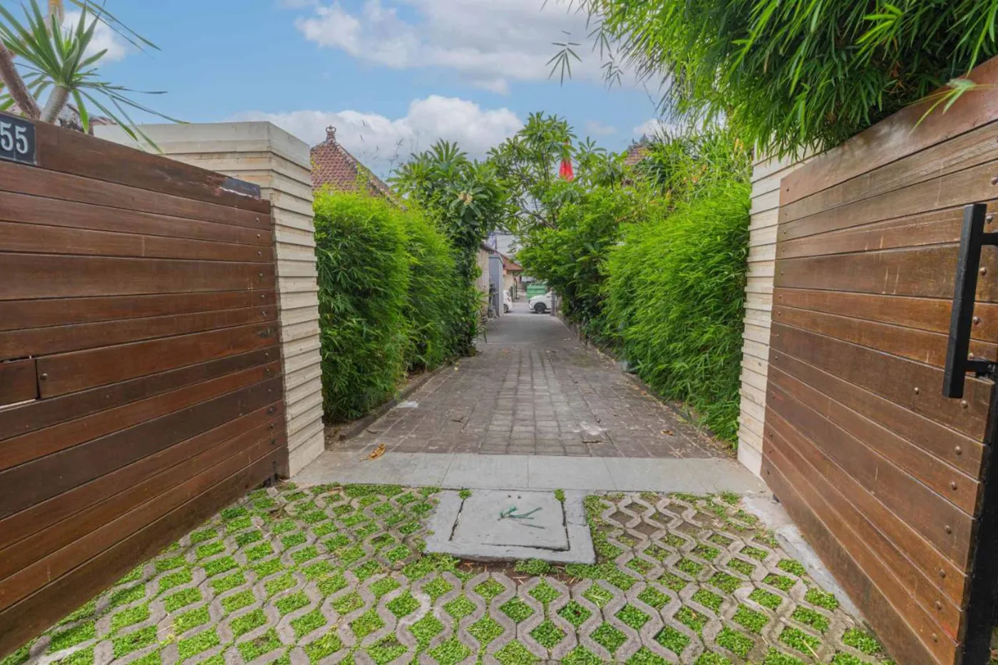 Modern Balinese villa interior: open kitchen with wooden cabinets, granite island, tiled backsplash, and dining table with pink orchids, overlooking a green balcony. - Bali Villas
