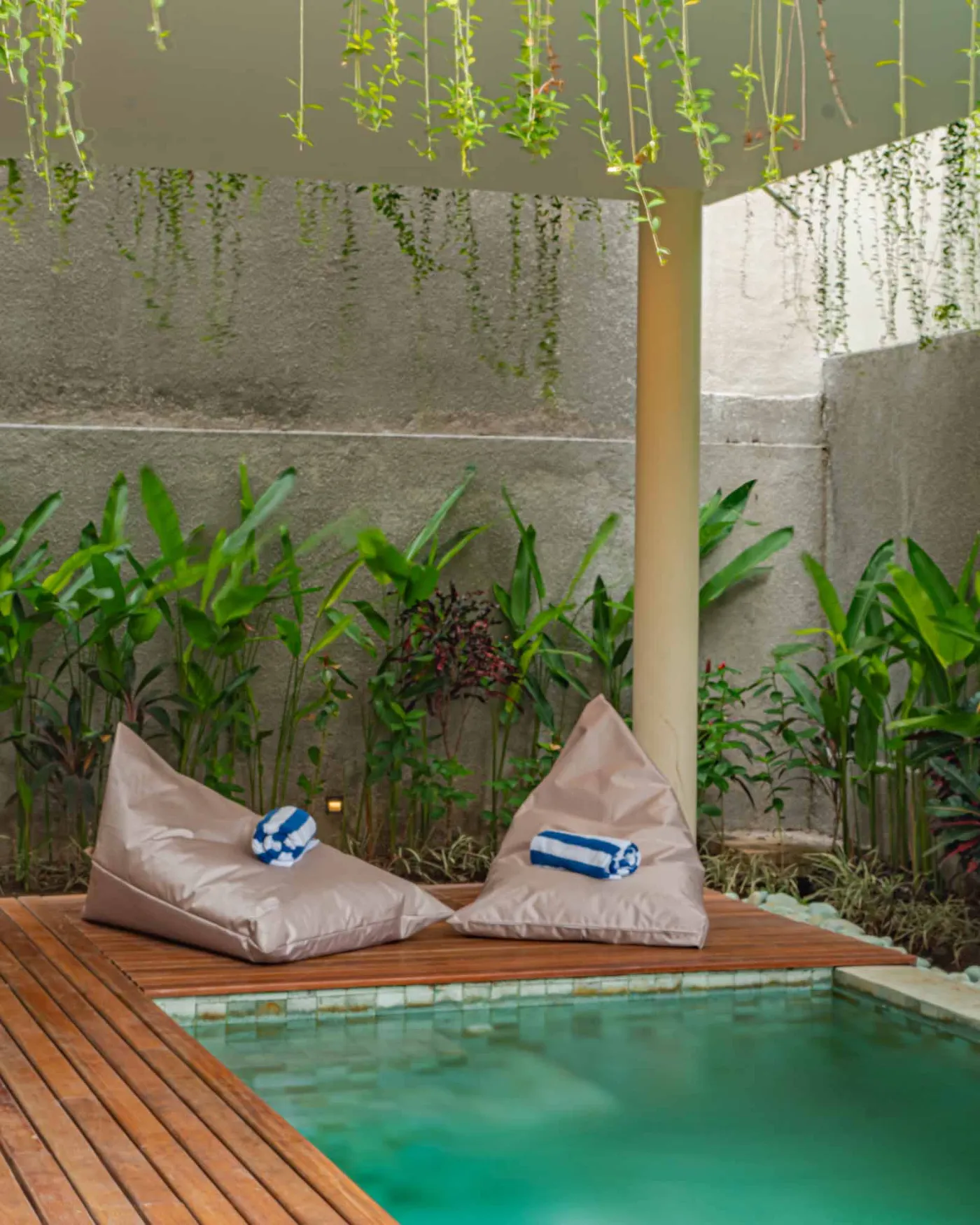 Spacious wooden kitchen and dining area in a tropical Balinese-style villa, featuring a set table with plates, glasses, vibrant floral centerpiece, and lush garden view through open sliding doors. - Bali Villas