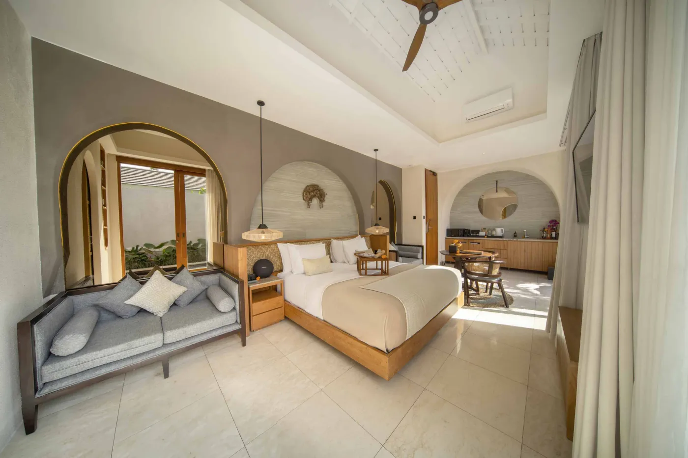 Spacious luxury tropical bedroom with king bed, wooden accents, ceiling fan, and poolside garden view through large windows. - Bali Villas