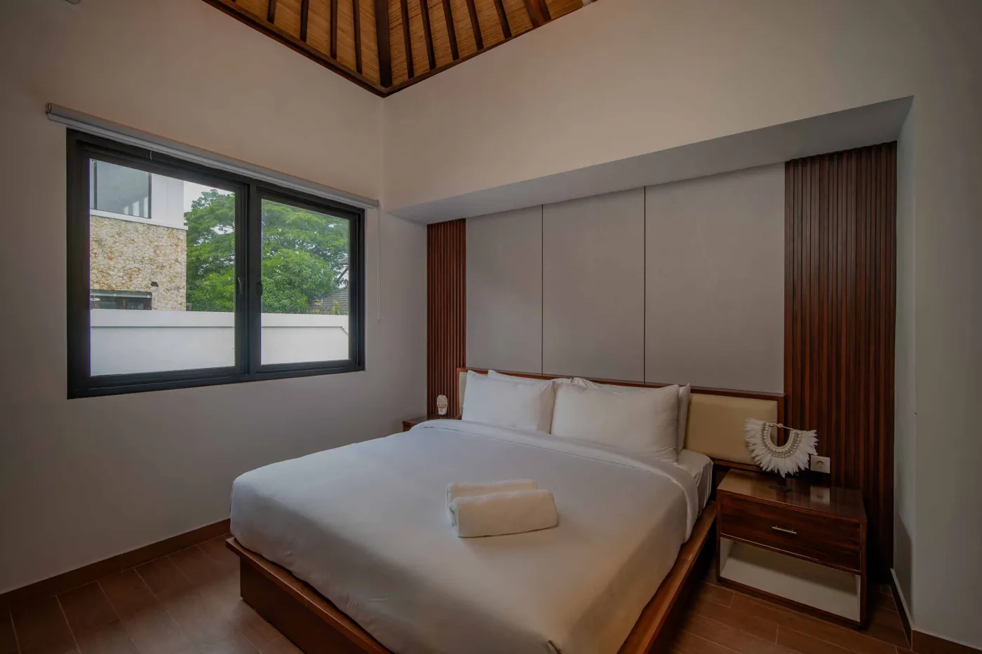 Modern hotel bathroom with double vanity sinks, large framed mirror, and frosted glass shower enclosure. - Bali Villas
