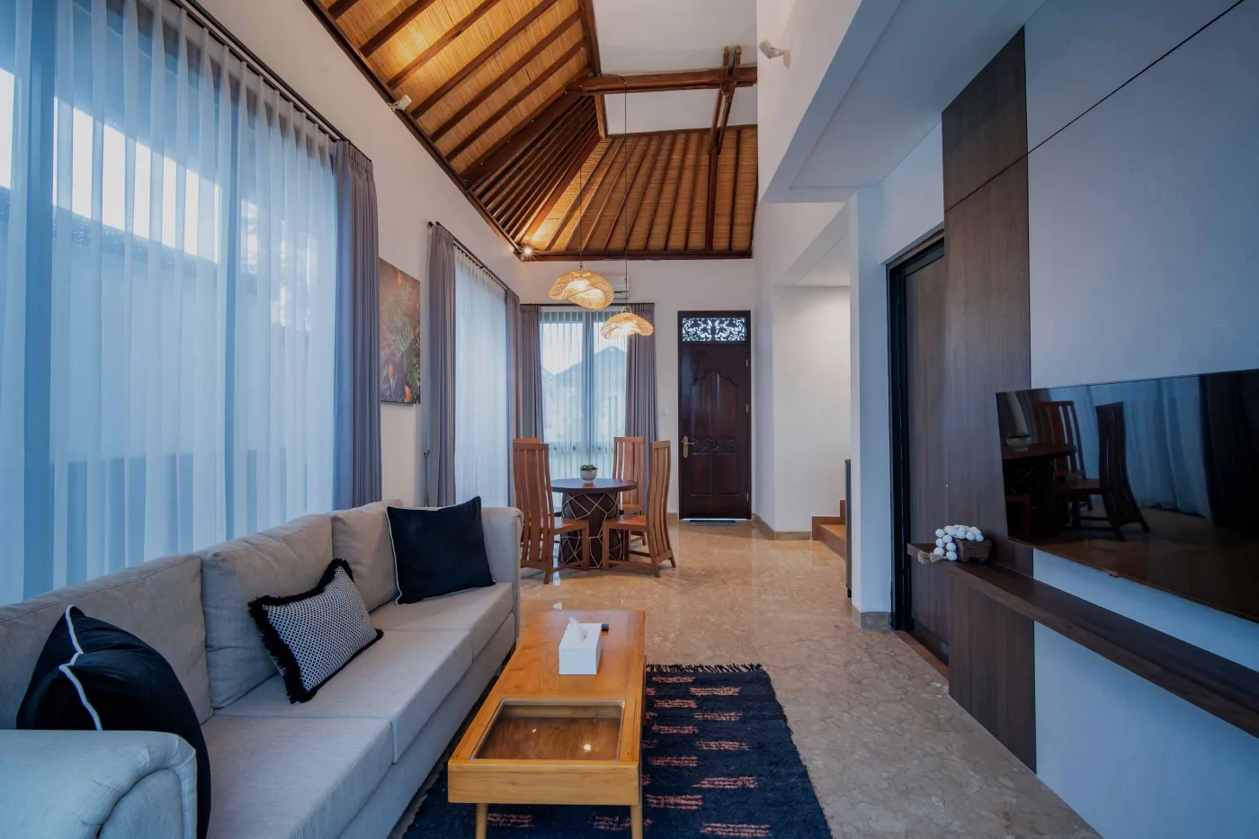 Modern hotel bathroom with double vanity sinks, large framed mirror, and frosted glass shower enclosure. - Bali Villas