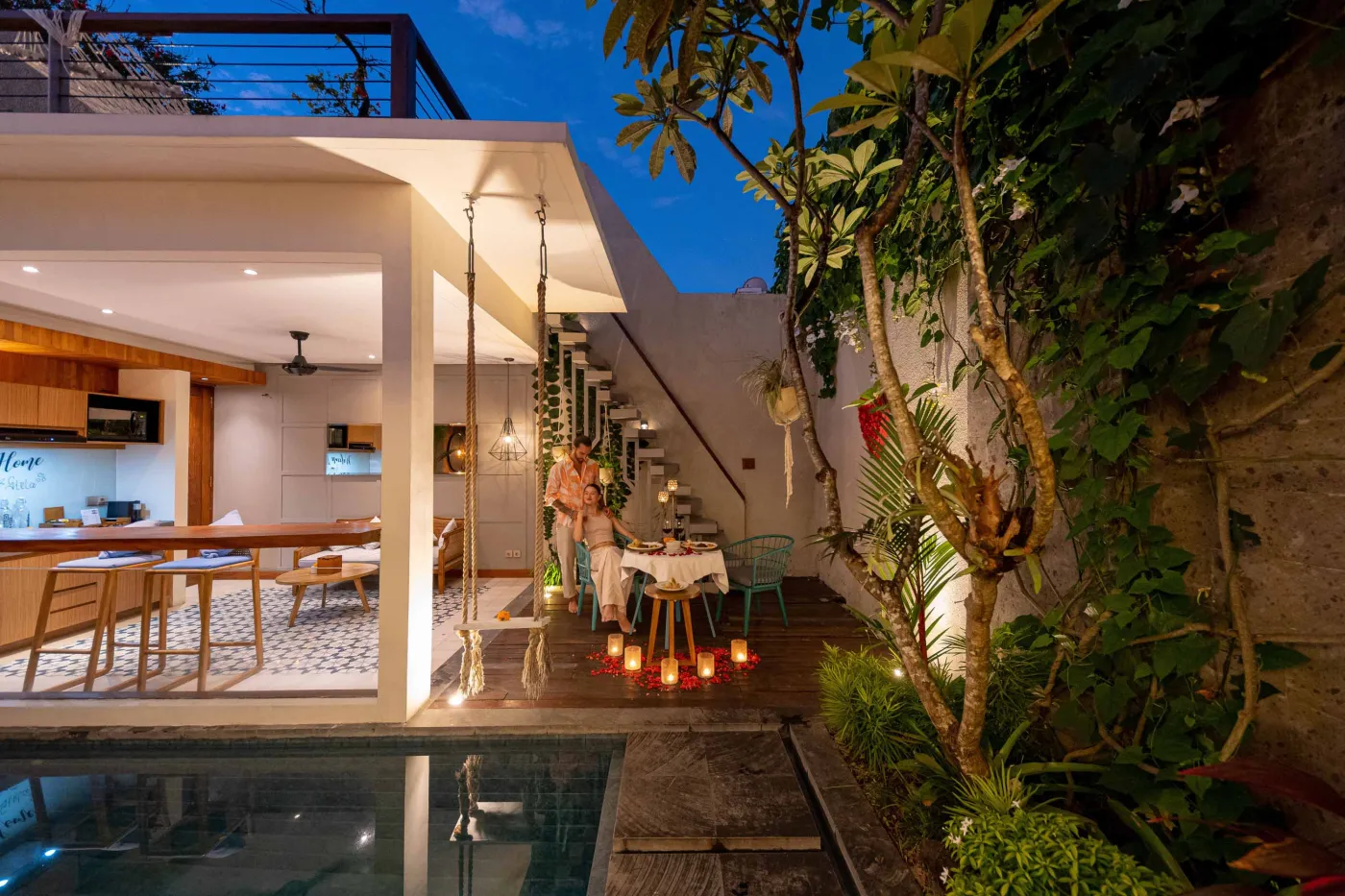 Romantic couple embracing on a modern balcony at sunset, surrounded by tropical plants. - Bali Villas