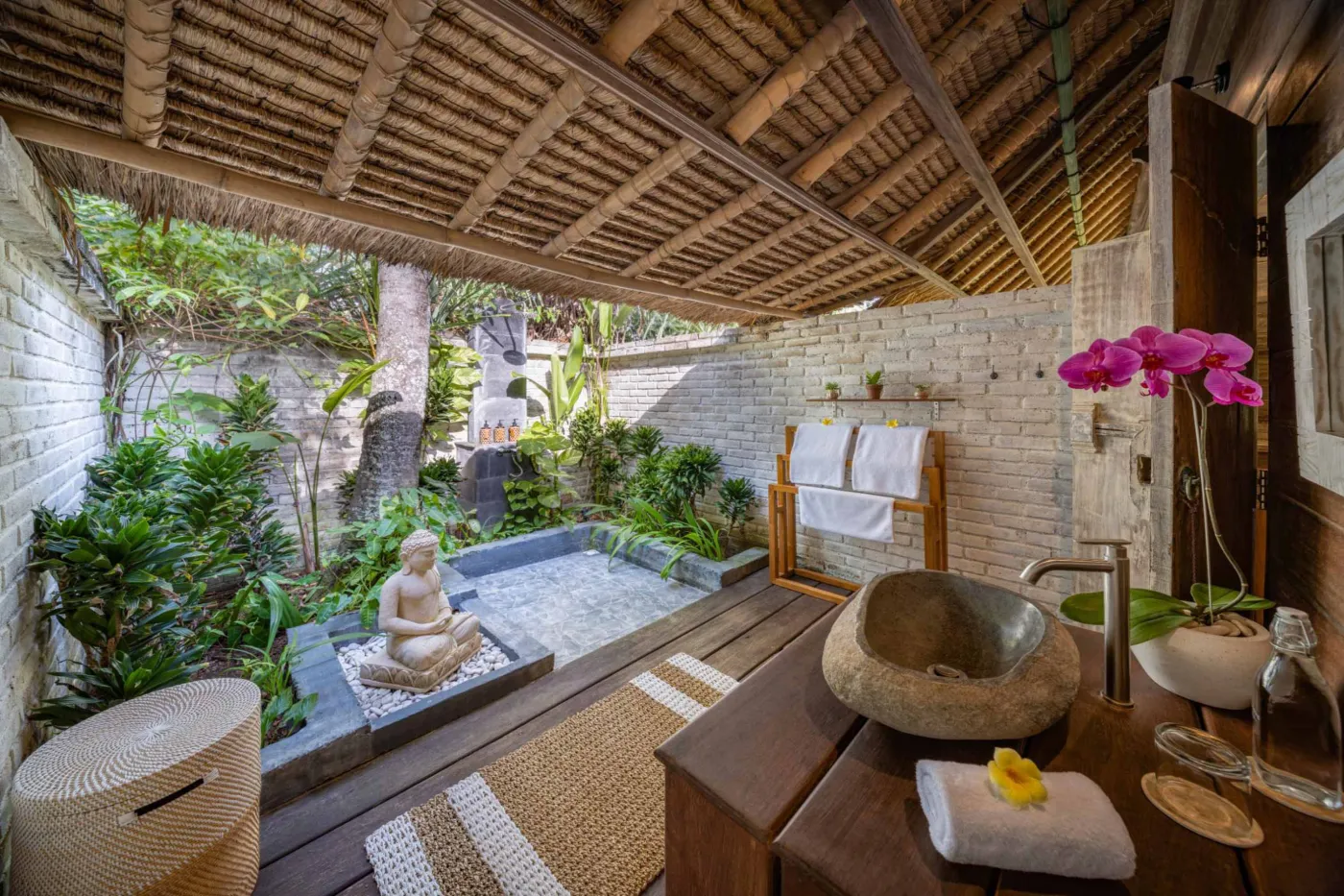 Luxurious Balinese veranda at sunset overlooking ocean and infinity pool, with wooden furniture, tropical plants, and cushioned seating. - Bali Villas