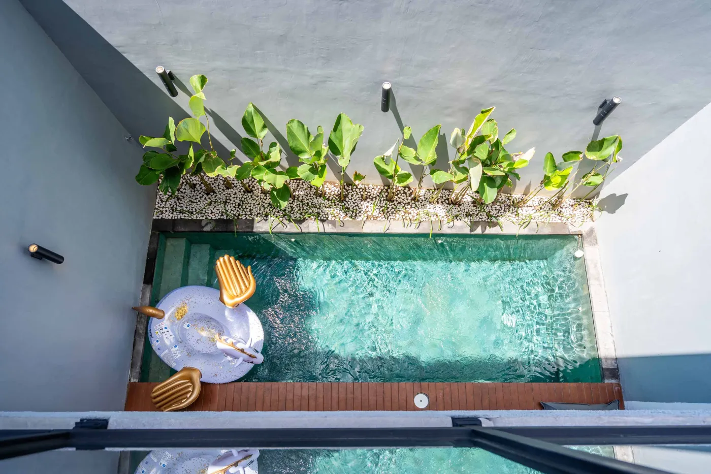 Modern Balinese-style bathroom with glass shower enclosure, round wooden mirror, stone vanity, and stacked towels. - Bali Villas