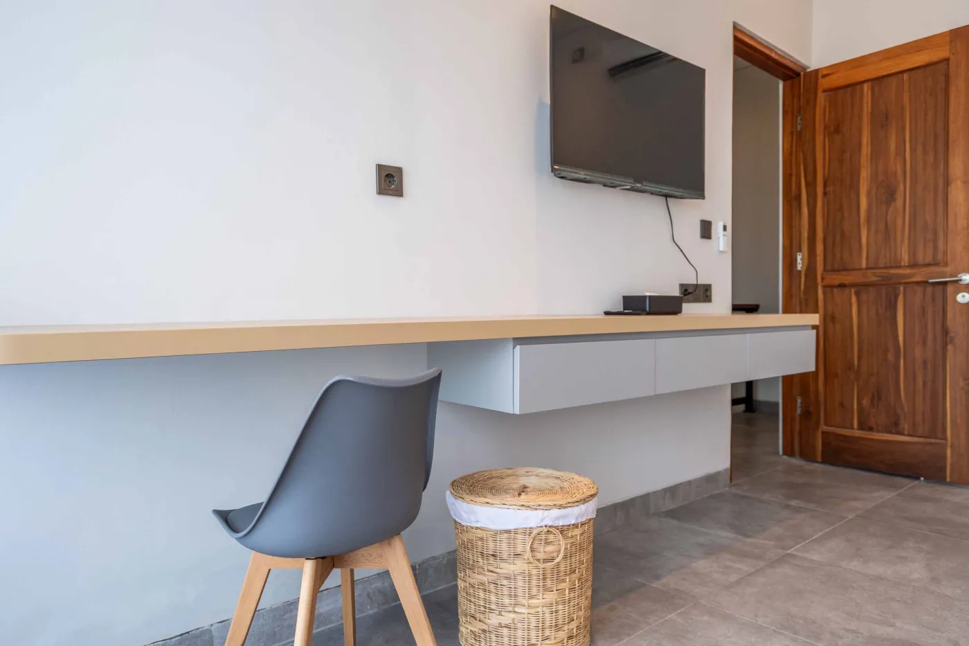 Modern Balinese-style bathroom with glass shower enclosure, round wooden mirror, stone vanity, and stacked towels. - Bali Villas