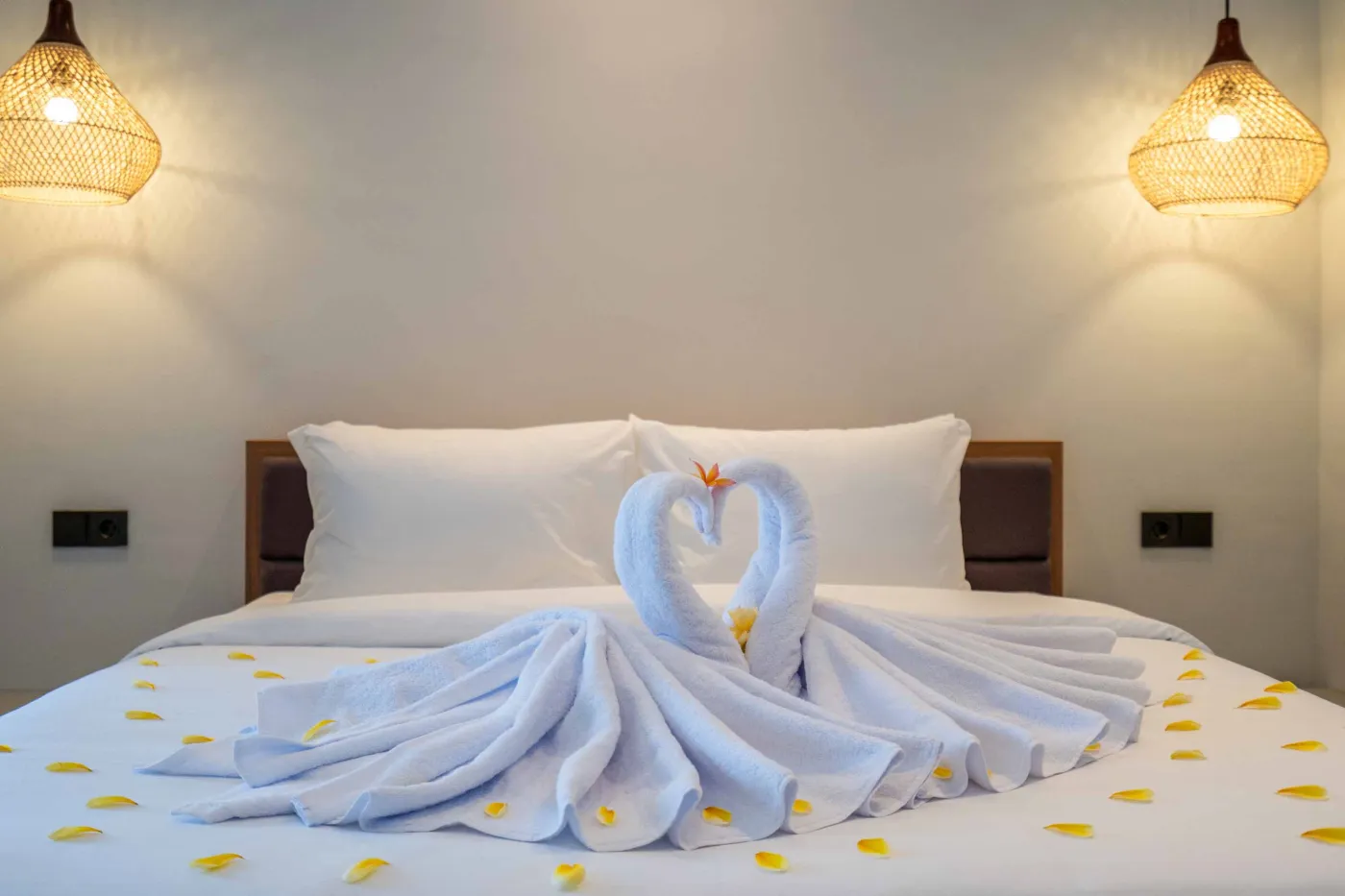Modern Balinese-style bathroom with glass shower enclosure, round wooden mirror, stone vanity, and stacked towels. - Bali Villas