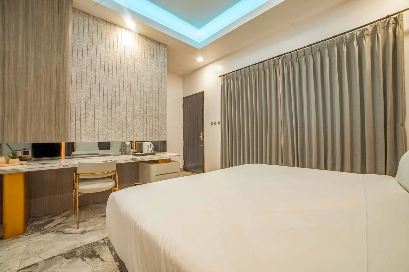 Modern luxury bathroom with LED-lit mirror, wooden vanity sink, white toilet, and beige marble-patterned tiled walls. - Bali Villas