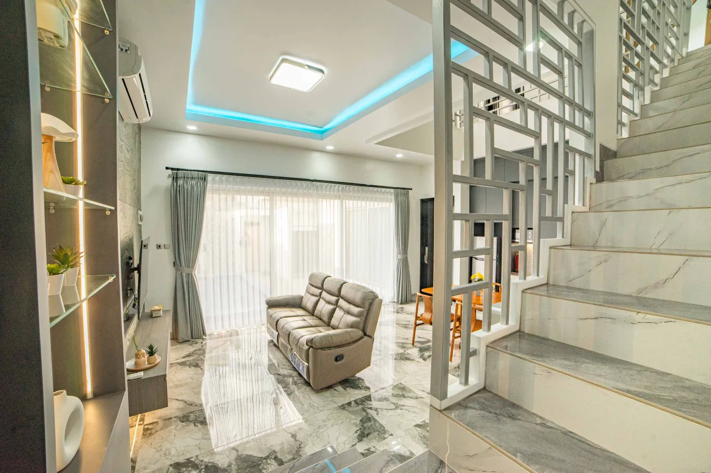 Modern luxury bathroom with LED-lit mirror, wooden vanity sink, white toilet, and beige marble-patterned tiled walls. - Bali Villas
