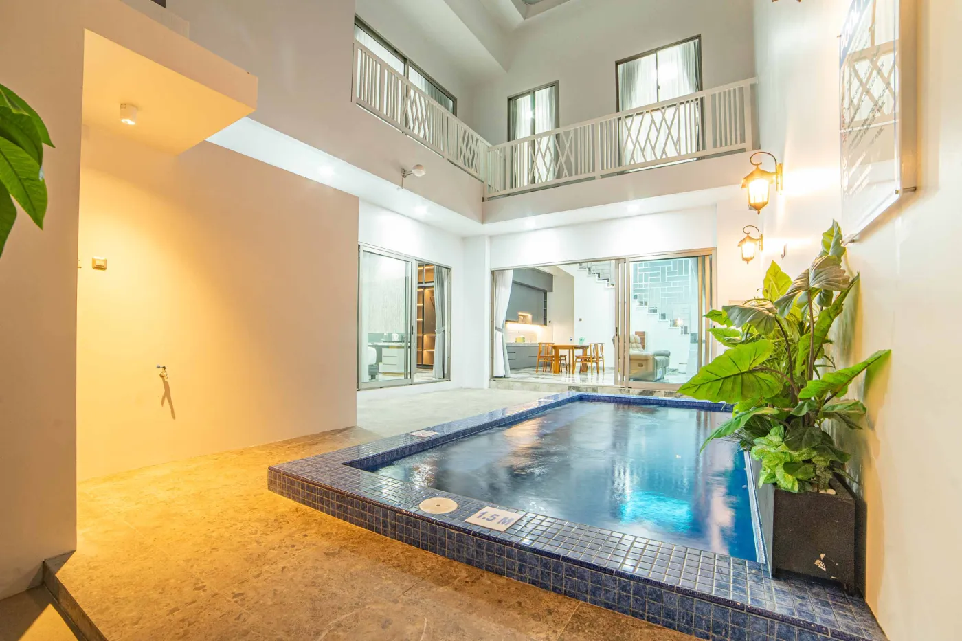 Modern luxury bathroom with LED-lit mirror, wooden vanity sink, white toilet, and beige marble-patterned tiled walls. - Bali Villas