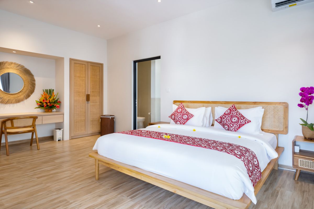 Modern tropical dining room with rustic wooden table, benches, red napkins, fruit bowls, and woven hanging lamp. - Bali Villas