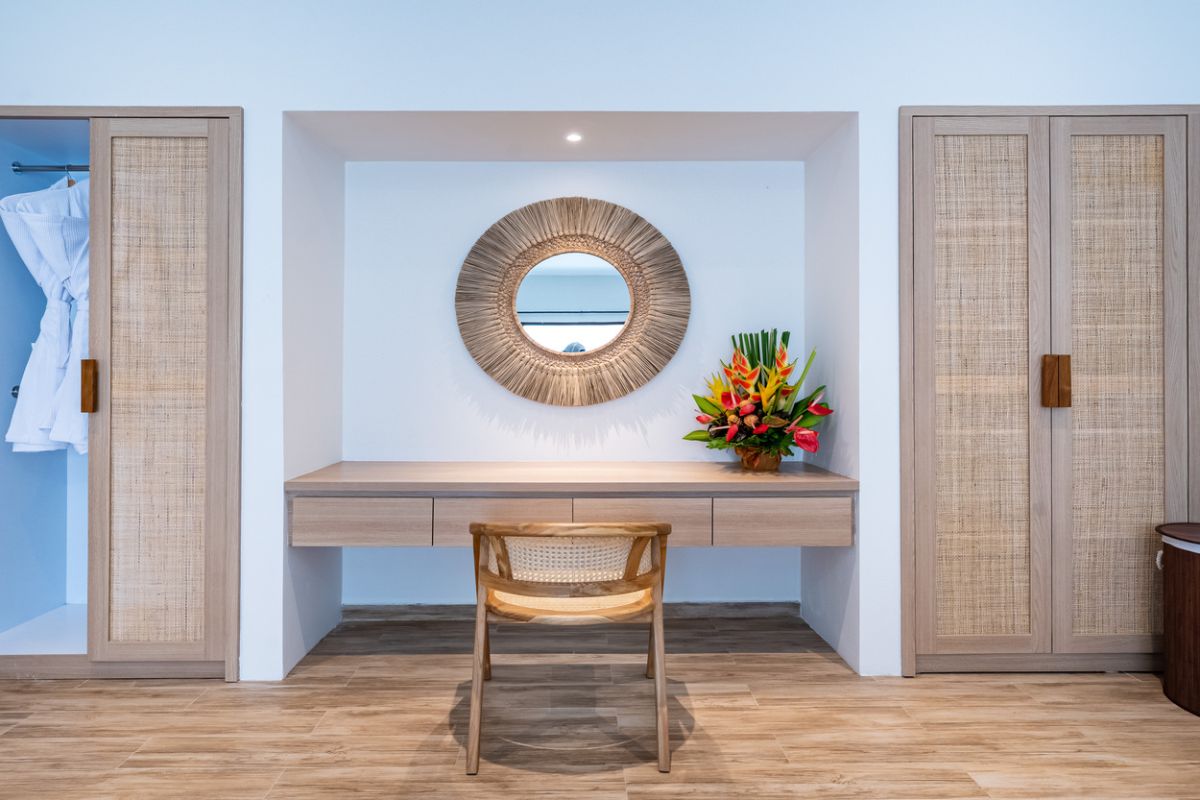 Modern tropical dining room with rustic wooden table, benches, red napkins, fruit bowls, and woven hanging lamp. - Bali Villas