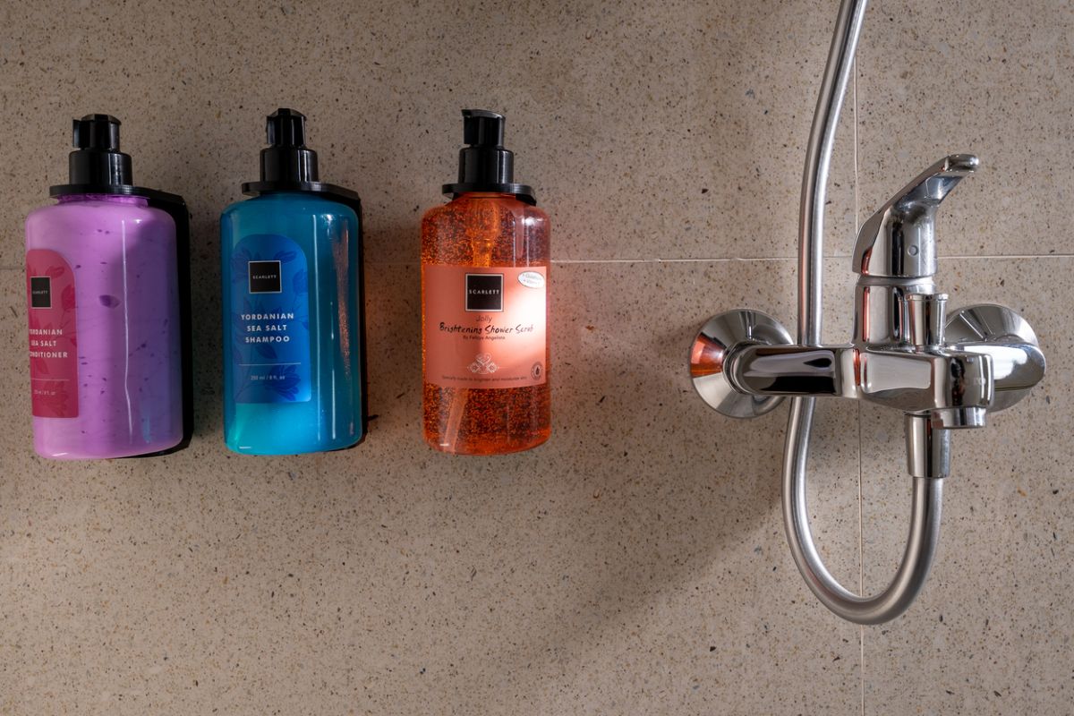 Modern tropical kitchen and dining area with wooden table, rattan chairs, hanging lamps, and infinity pool view through glass doors. - Bali Villas