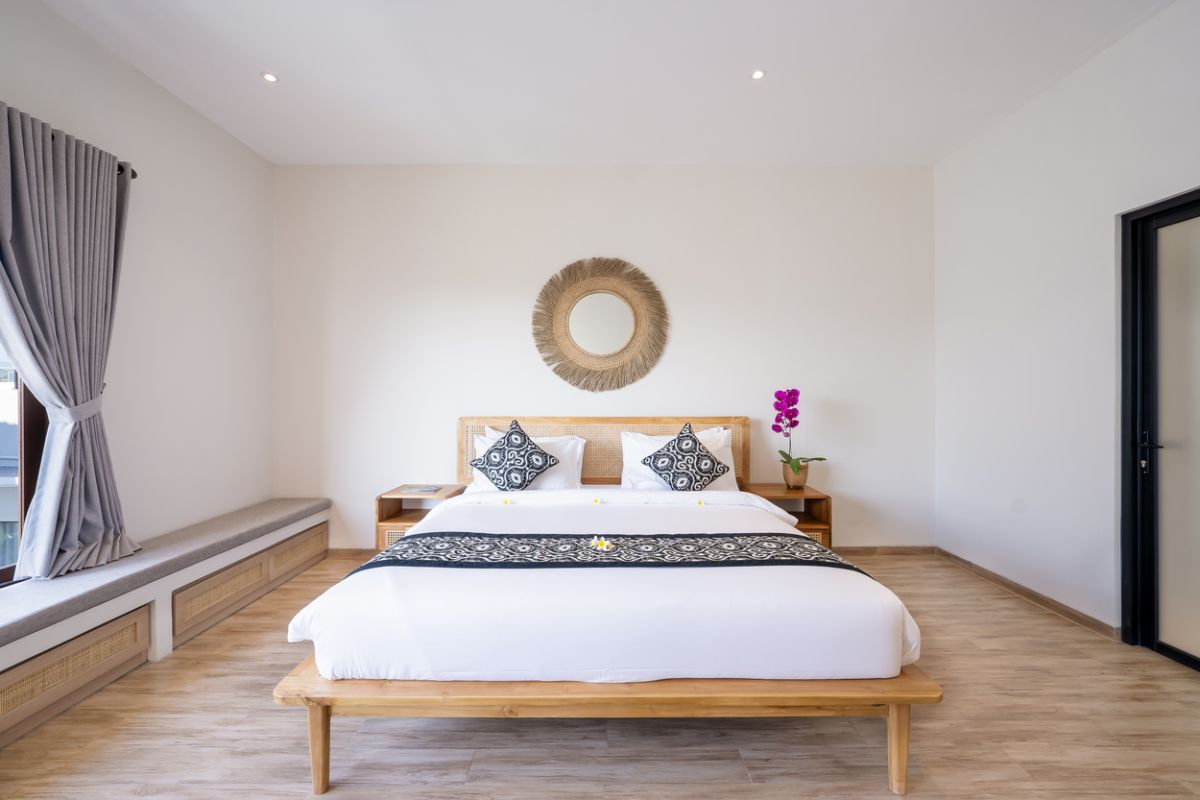 Modern tropical kitchen and dining area with wooden table, rattan chairs, hanging lamps, and infinity pool view through glass doors. - Bali Villas