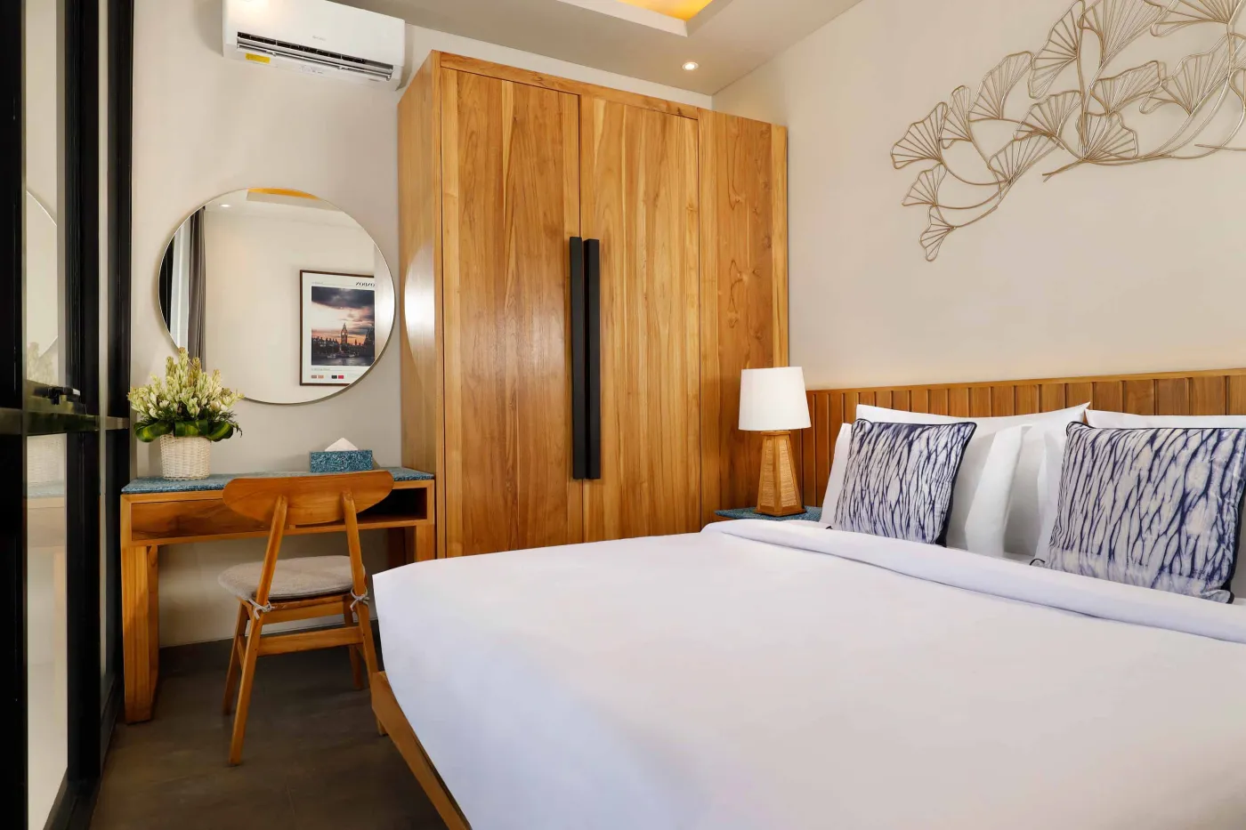 Modern spa bathroom featuring wooden vanity with round sink, oval mirror, white toilet, and petal-filled freestanding tub. - Bali Villas