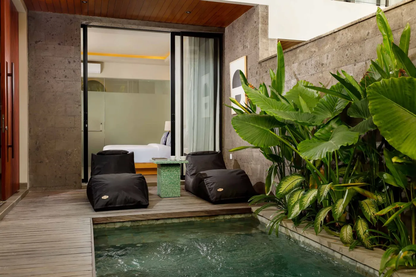 Modern spa bathroom featuring wooden vanity with round sink, oval mirror, white toilet, and petal-filled freestanding tub. - Bali Villas