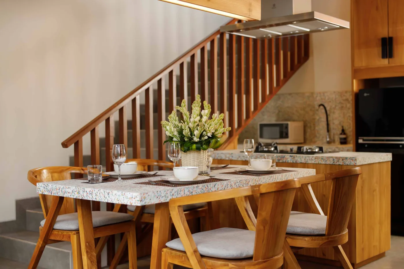 Modern spa bathroom featuring wooden vanity with round sink, oval mirror, white toilet, and petal-filled freestanding tub. - Bali Villas