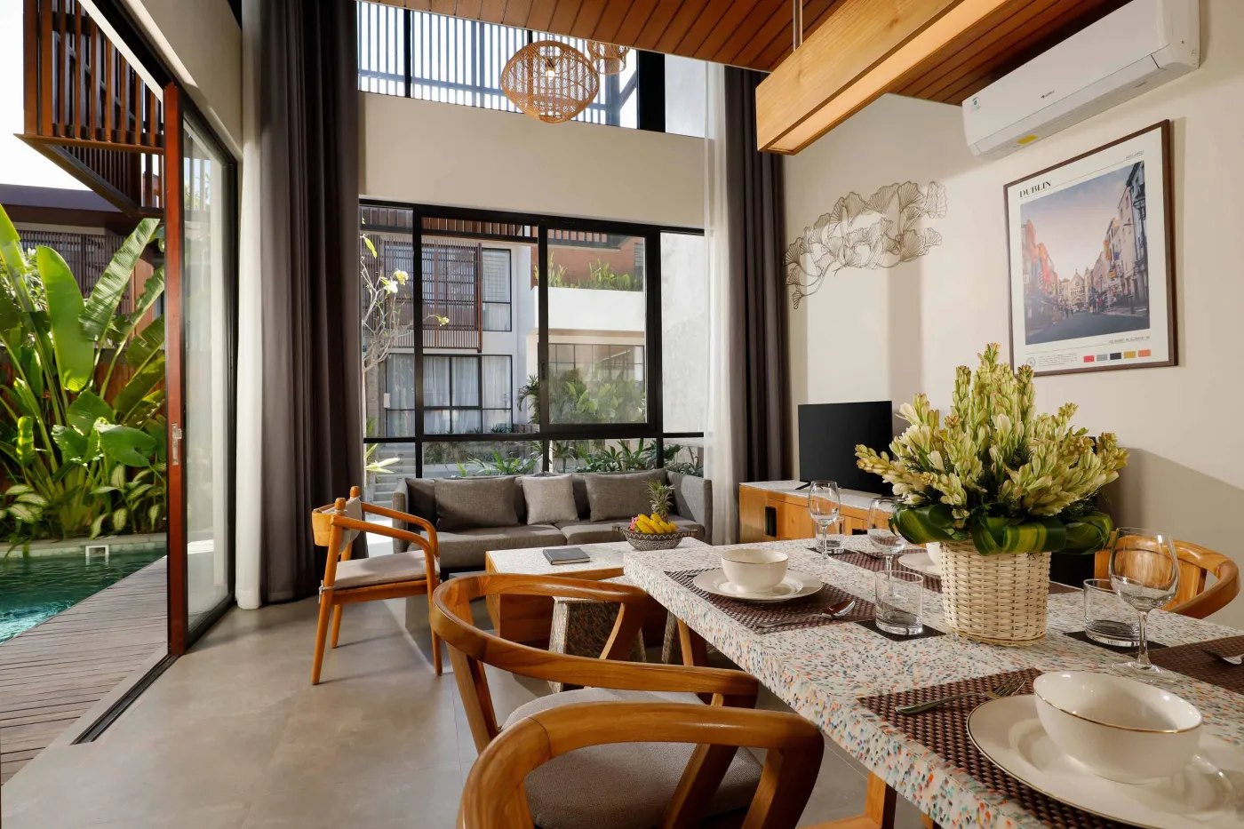 Modern spa bathroom featuring wooden vanity with round sink, oval mirror, white toilet, and petal-filled freestanding tub. - Bali Villas