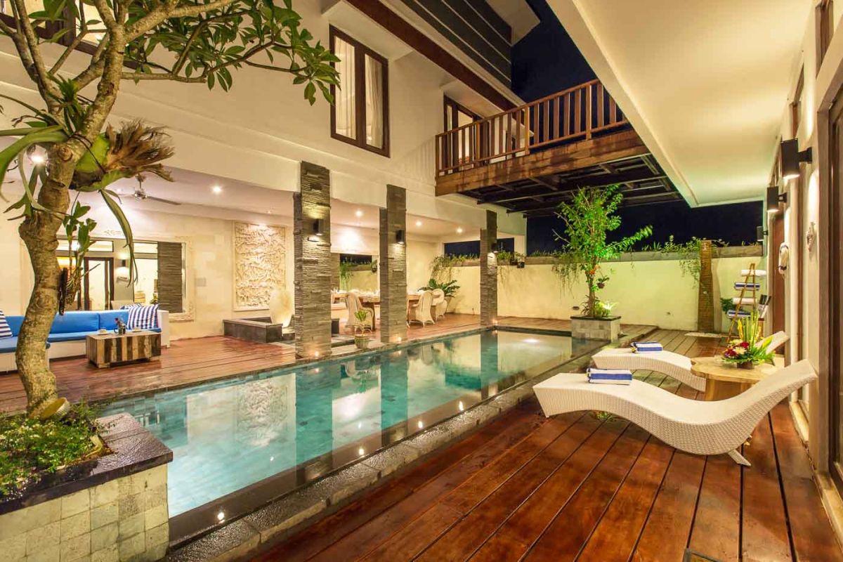 Luxurious Balinese bathroom with freestanding stone bathtub, tropical garden view, and floating frangipani petals. - Bali Villas