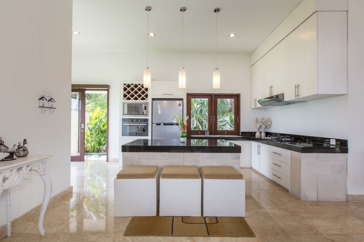 Luxurious Balinese bathroom with freestanding stone bathtub, tropical garden view, and floating frangipani petals. - Bali Villas