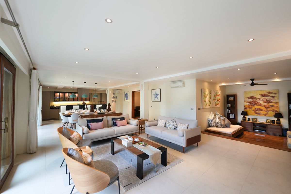 Modern open-plan kitchen with white cabinets, black granite island, stainless steel appliances, and tropical wood accents. - Bali Villas