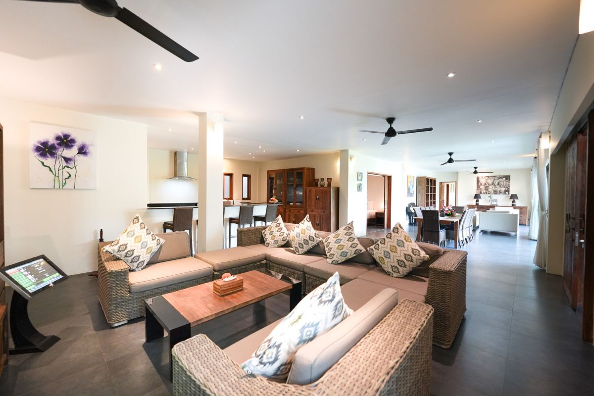 Modern open-plan kitchen with white cabinets, black granite island, stainless steel appliances, and tropical wood accents. - Bali Villas