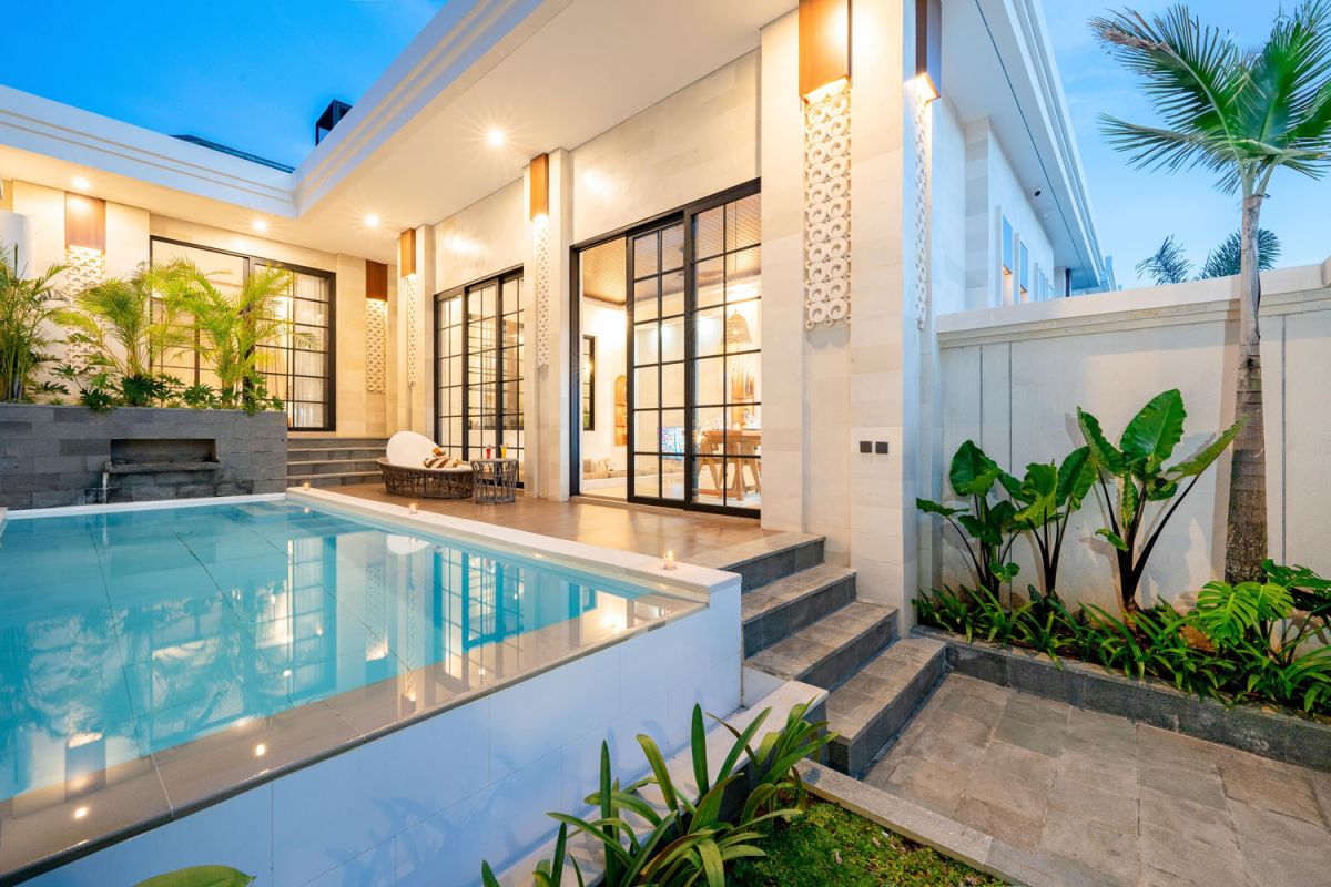 Modern Bali villa infinity pool and outdoor lounge with tropical plants at dusk. - Bali Villas