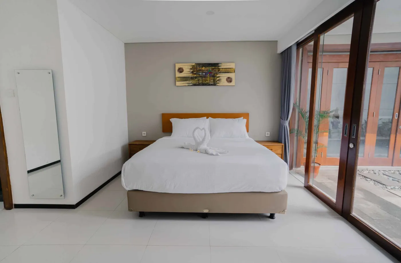 Modern bathroom with white toilet, sink vanity, wooden wardrobe, and round mirror on white brick walls. - Bali Villas