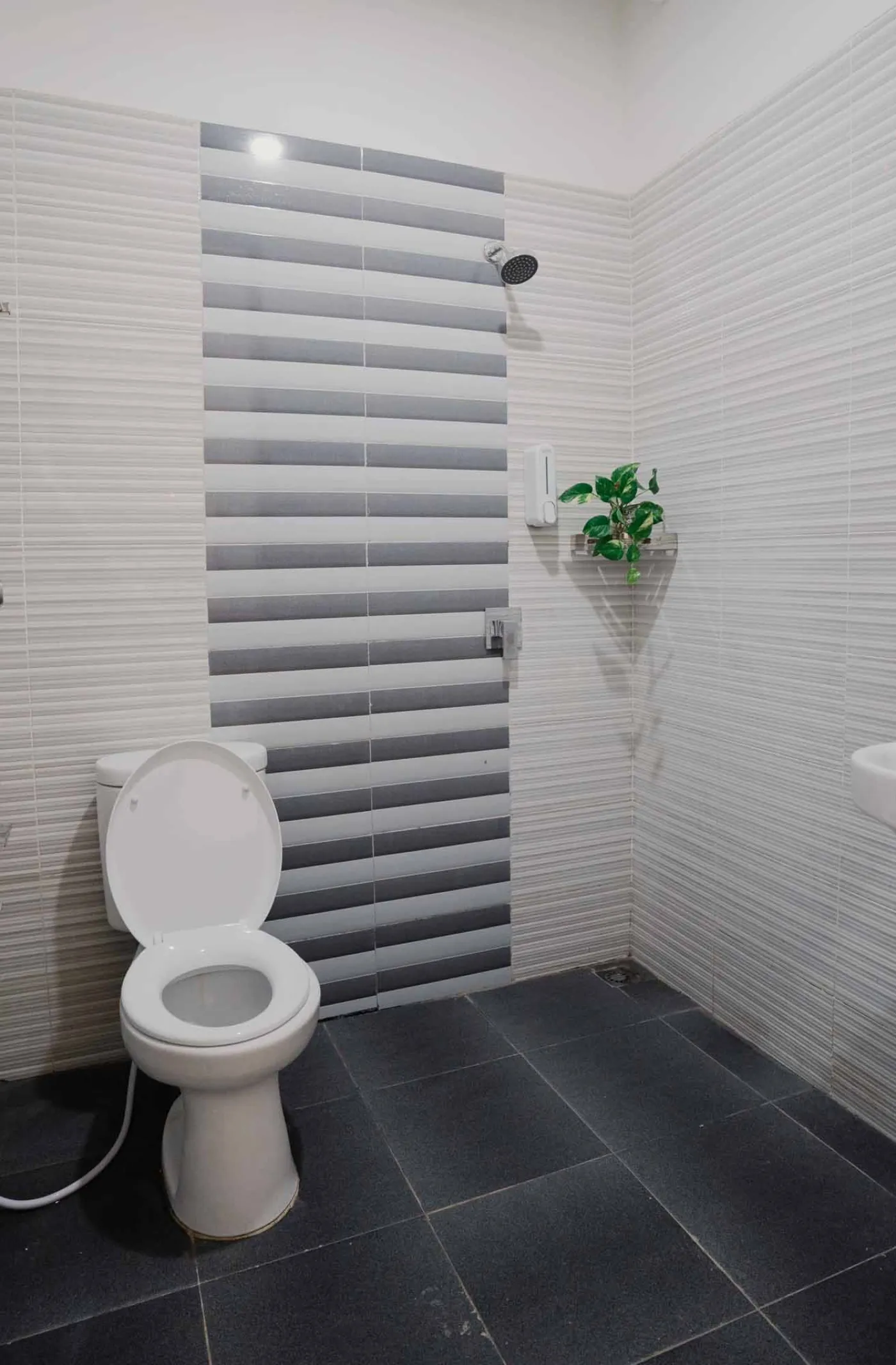 Modern bathroom with white toilet, sink vanity, wooden wardrobe, and round mirror on white brick walls. - Bali Villas