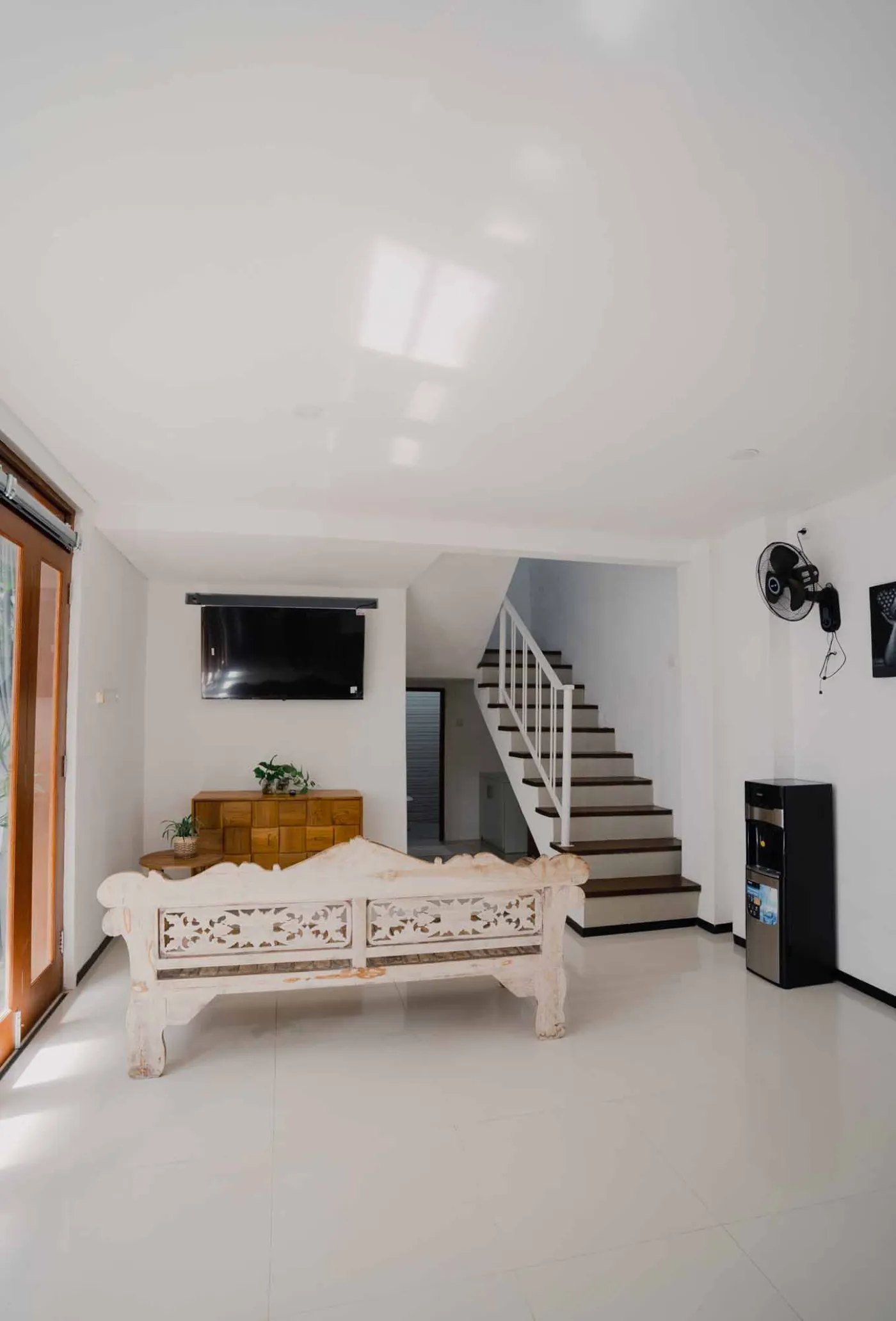 Modern bathroom with white toilet, sink vanity, wooden wardrobe, and round mirror on white brick walls. - Bali Villas
