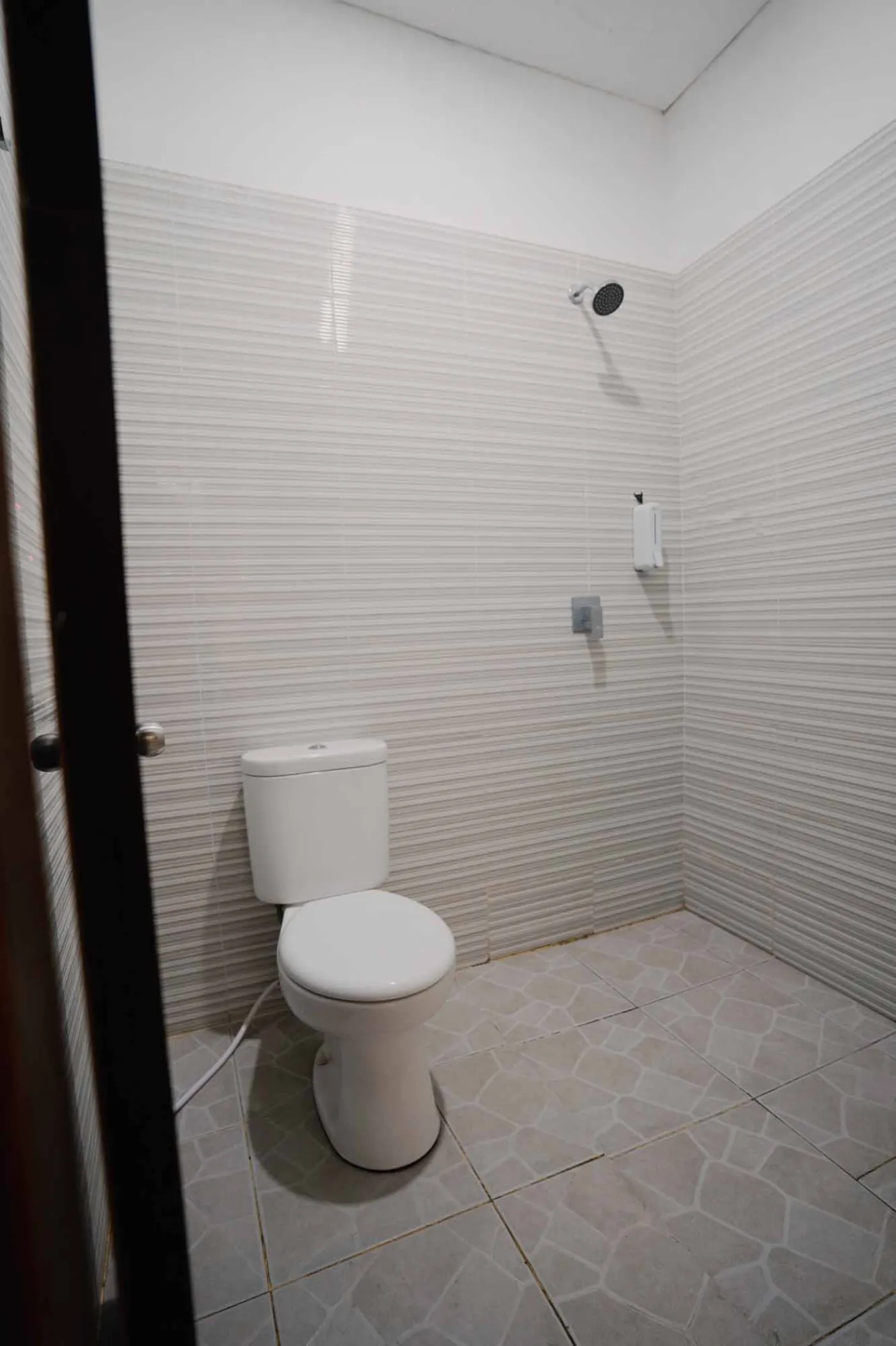 Modern bathroom with white toilet, sink vanity, wooden wardrobe, and round mirror on white brick walls. - Bali Villas