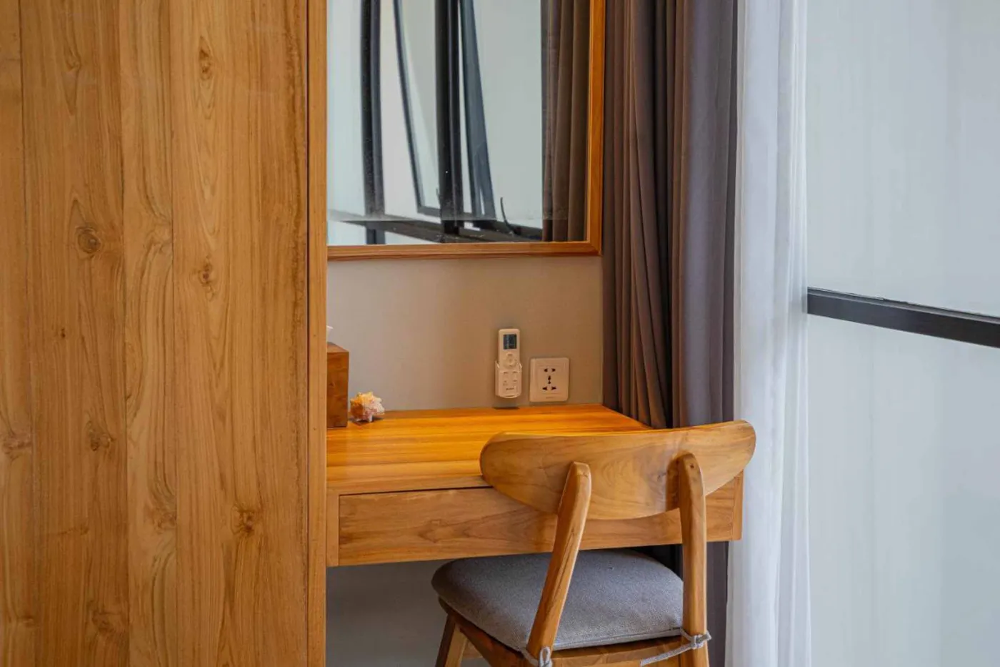 Woven bamboo pendant lights hanging in a modern tropical room with gray curtains, wooden shelves, and infinity pool view. - Bali Villas