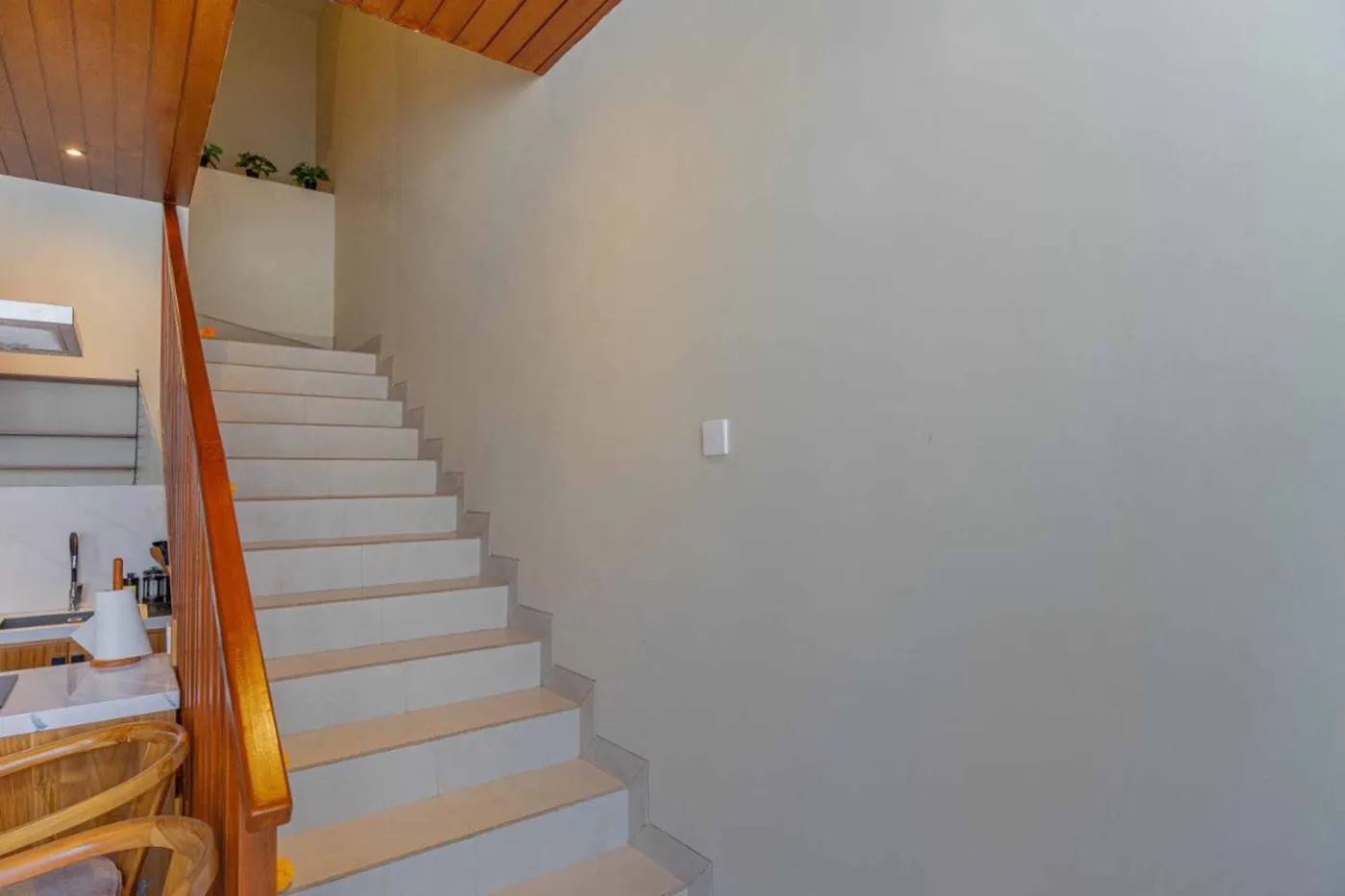 Woven bamboo pendant lights hanging in a modern tropical room with gray curtains, wooden shelves, and infinity pool view. - Bali Villas