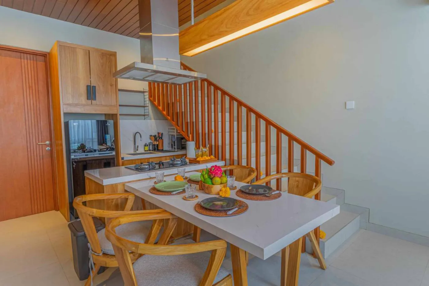Woven bamboo pendant lights hanging in a modern tropical room with gray curtains, wooden shelves, and infinity pool view. - Bali Villas