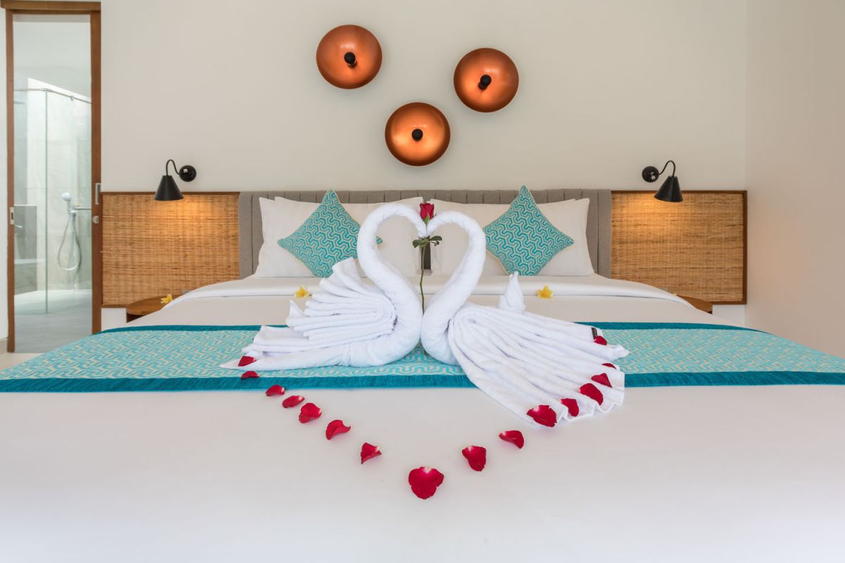 Modern tropical Bali villa interior with neutral-toned sofas, wooden dining set, potted orchids, and infinity pool view through glass doors. - Bali Villas