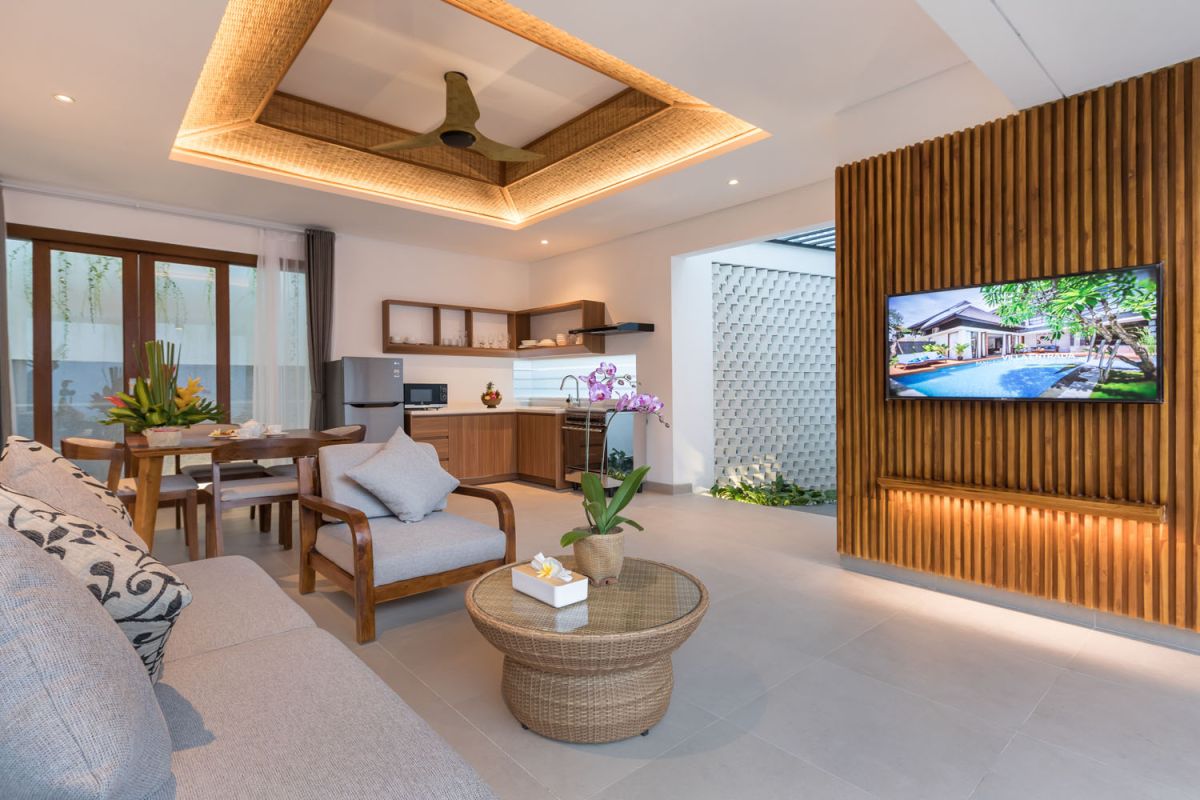 Modern tropical Bali villa interior with neutral-toned sofas, wooden dining set, potted orchids, and infinity pool view through glass doors. - Bali Villas