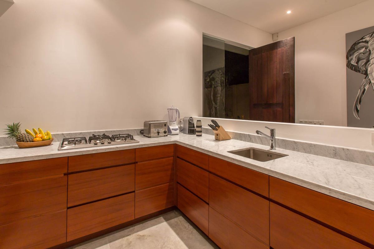 Modern luxury bathroom with wooden double vanity, white marble countertop, orchids, and folded towels. - Bali Villas